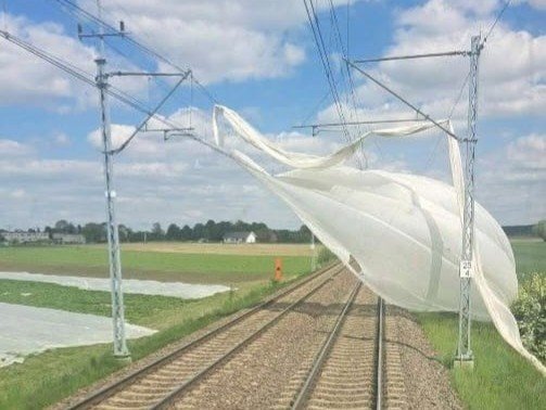 Niewłaściwie zabezpieczona agrowłóknina została zwiana z pola i zawisła na sieci trakcyjnej. Do jej usunięcia konieczna była interwencja zespołu technicznego z pociągiem sieciowym. (fot. PKP PLK)